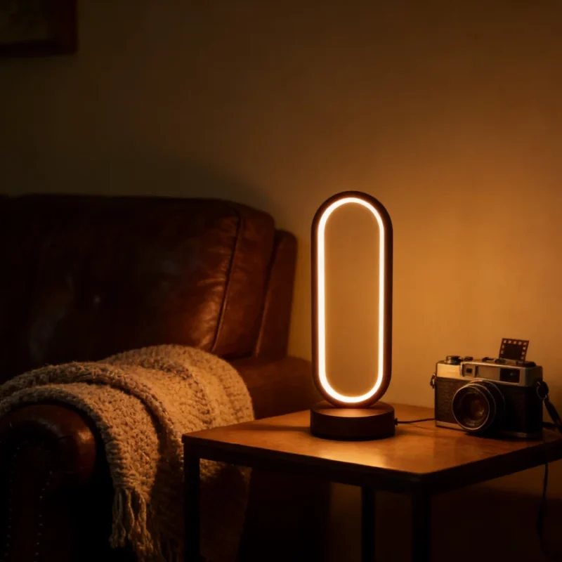Ovale led-ringtafellamp die warm brandt op een bijzettafel naast een leren bank en een vintage camera