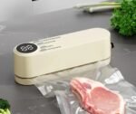 Crèmekleurig vacuümapparaat dat een zak vlees seal op een marmeren aanrecht